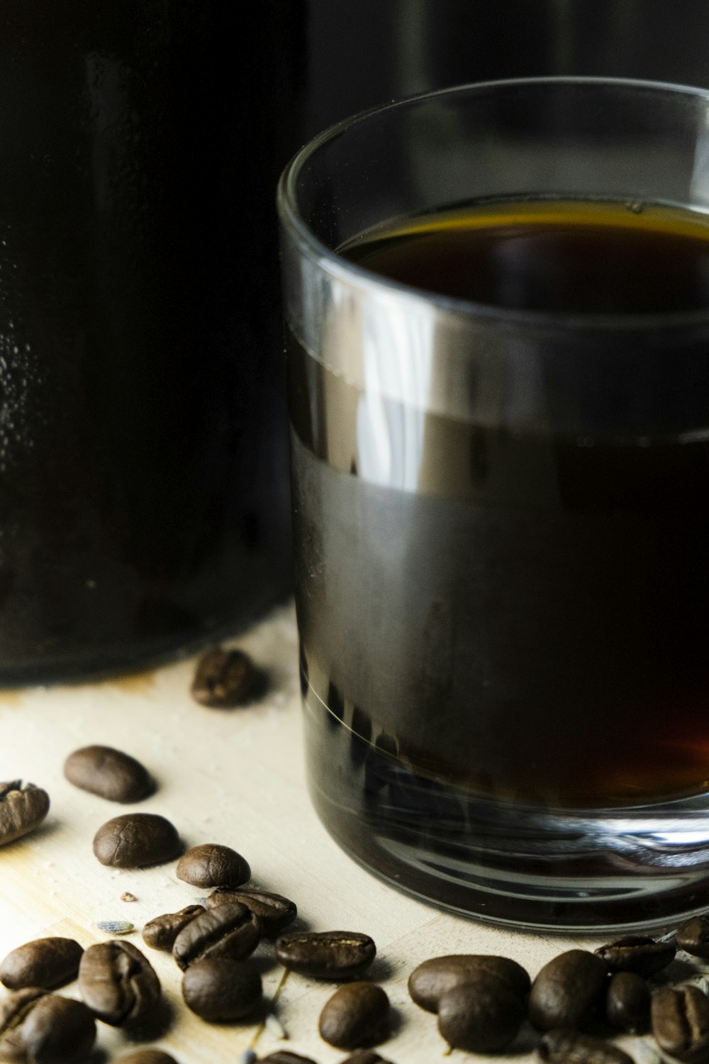 a glass of coffee sitting next to a bottle of coffee