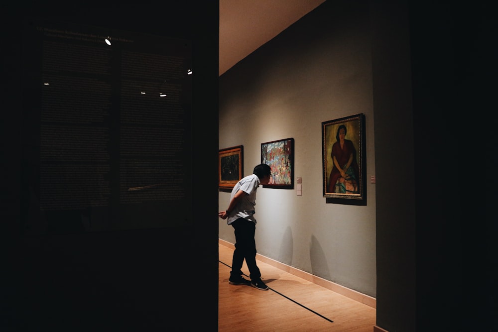 man wearing white shirt standing beside painting screenshot