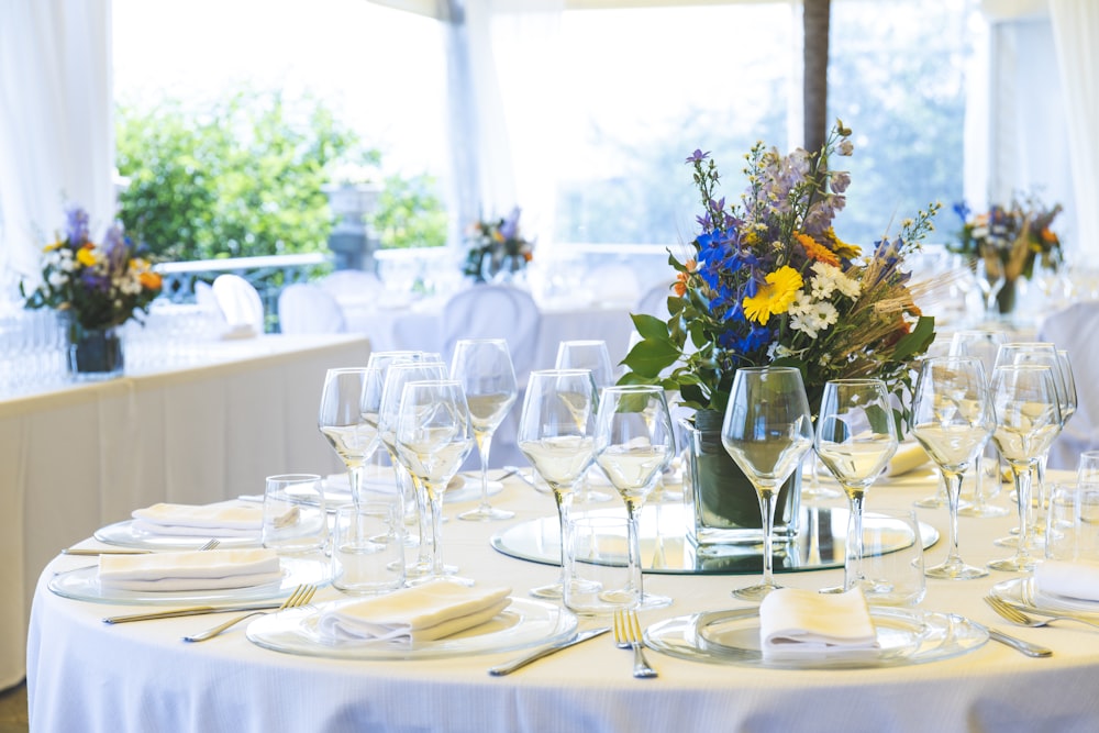 테이블 위의 꽃 중앙 장식품 근처 테이블 위의 투명한 긴 줄기 와인 잔