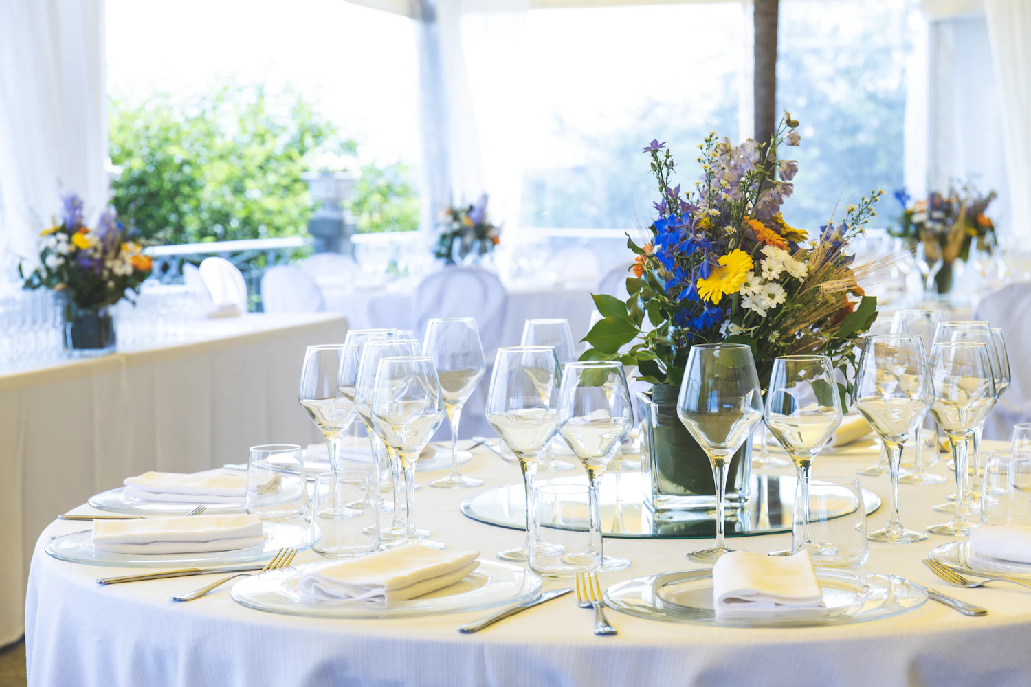 Wine glasses crowded around a low centrepiece on a dressed table