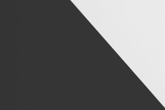 A minimalist composition featuring a diagonal division between two solid colors, black on the left and white on the right. The sharp contrast and clean lines create a striking geometric effect.