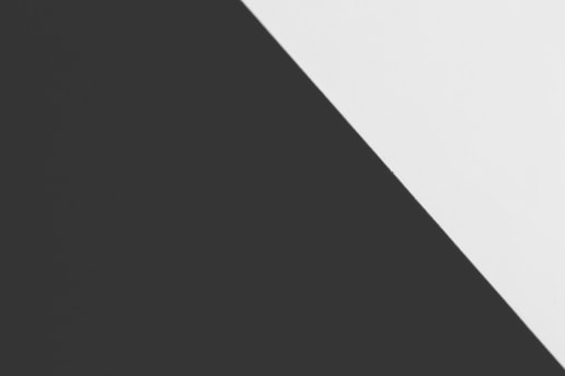 A minimalist composition featuring a diagonal division between two solid colors, black on the left and white on the right. The sharp contrast and clean lines create a striking geometric effect.