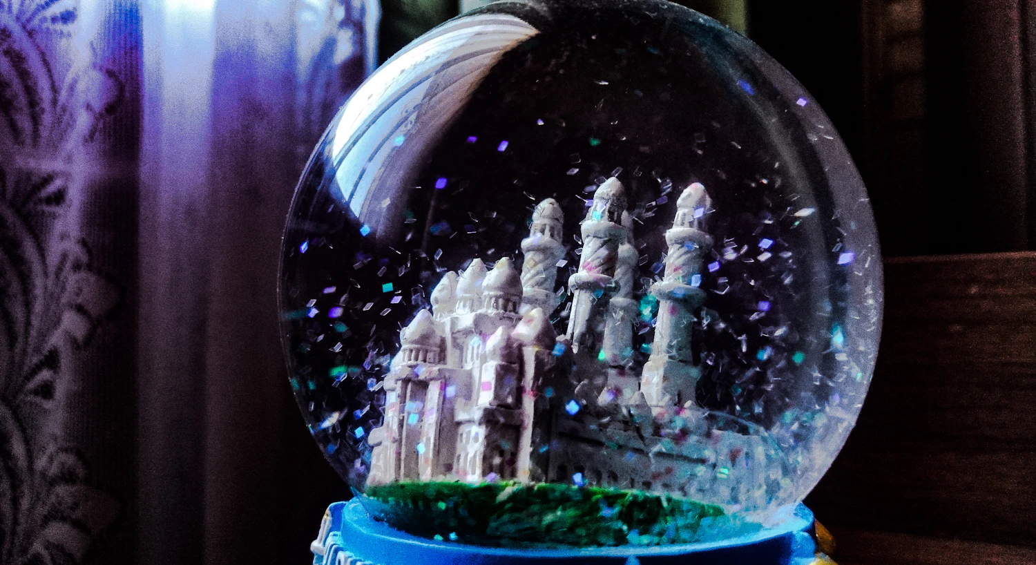 Winterburg snow globe: a white castle under falling glitter on a blue base
