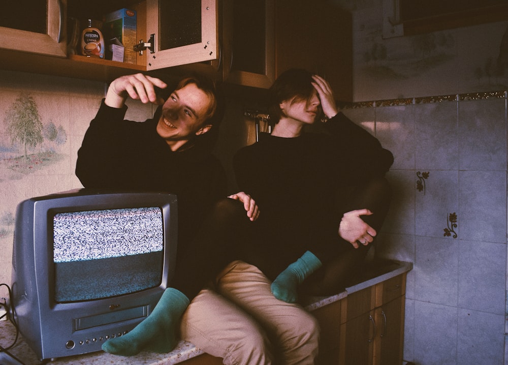 two men sitting beside CRT TV