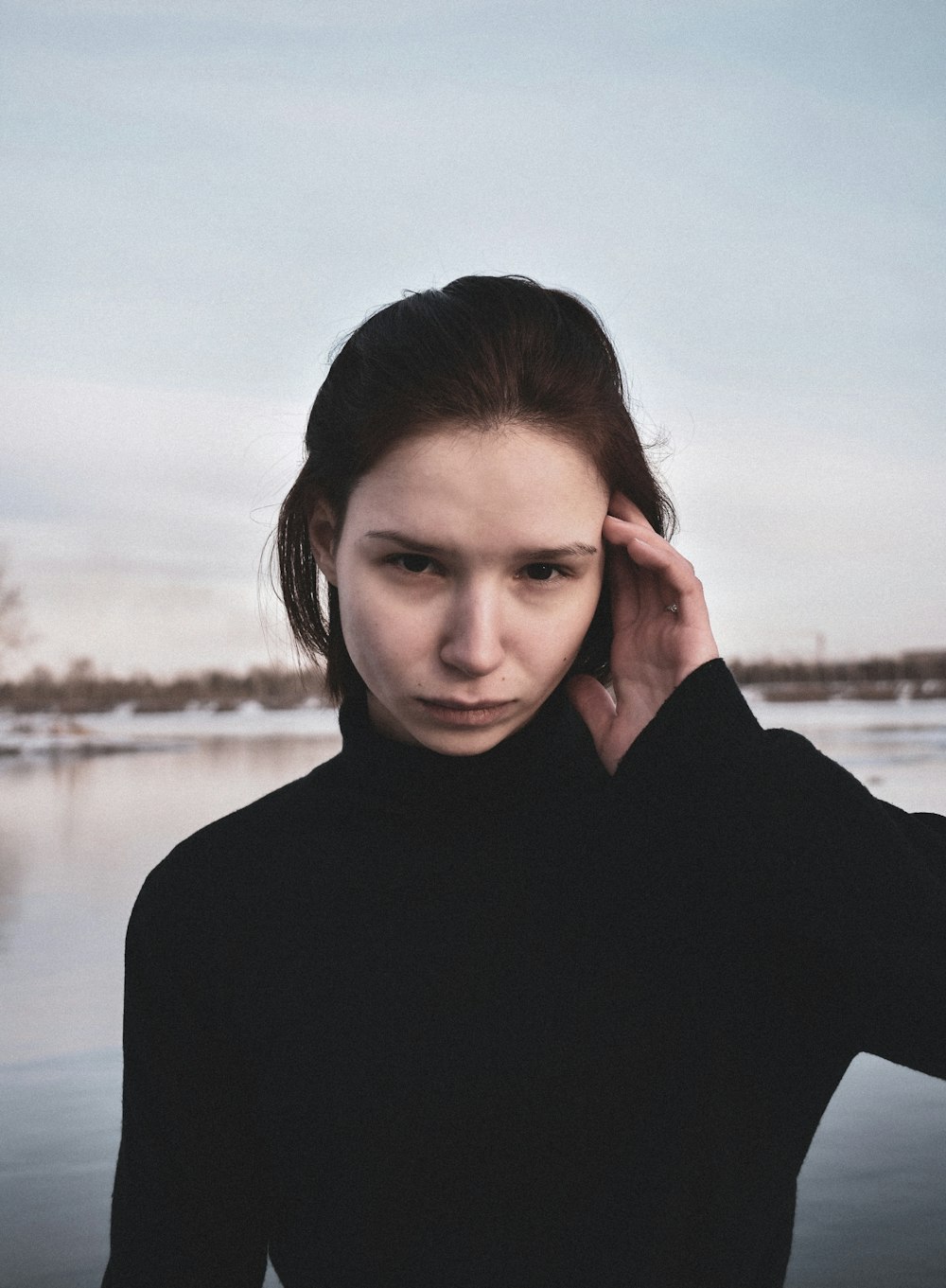 a woman in a black shirt is holding her hand to her ear