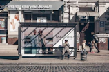 Street-level view of a bus stop wrapped in eye-catching graphics promoting a sustainable fashion line.