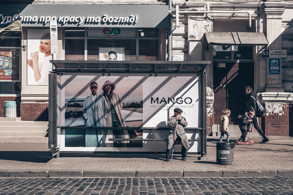 man wearing coat sitting on bus stop