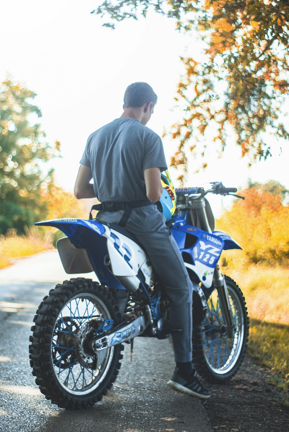 man in grey t-shirt sitting on blue and white dirt bike