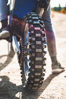 Close-up of a motorcycle tire with deep treads on a sunny day.