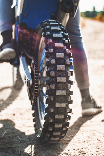 Close-up of a dirt bike’s knobby tire and suspension, showing signs of careful maintenance.