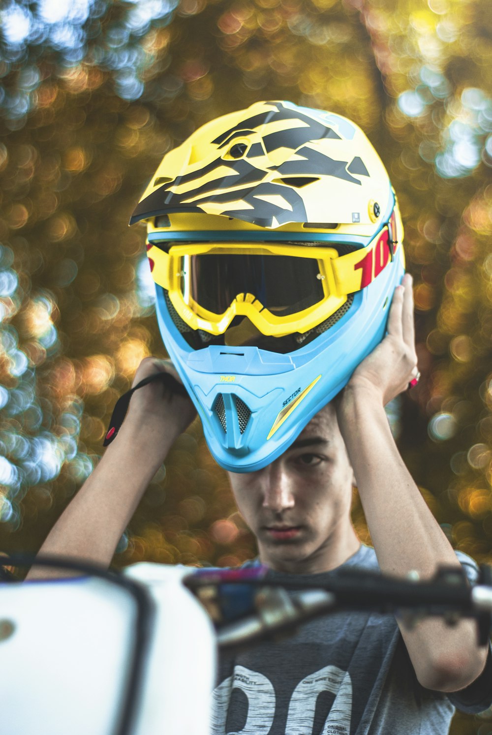 man holding yellow and blue motocross helmet