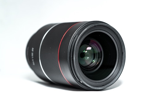 Close-up of a high-quality camera lens with a red accent background.