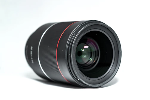 A sleek black and white close-up of a vintage film camera lens with subtle red accents.