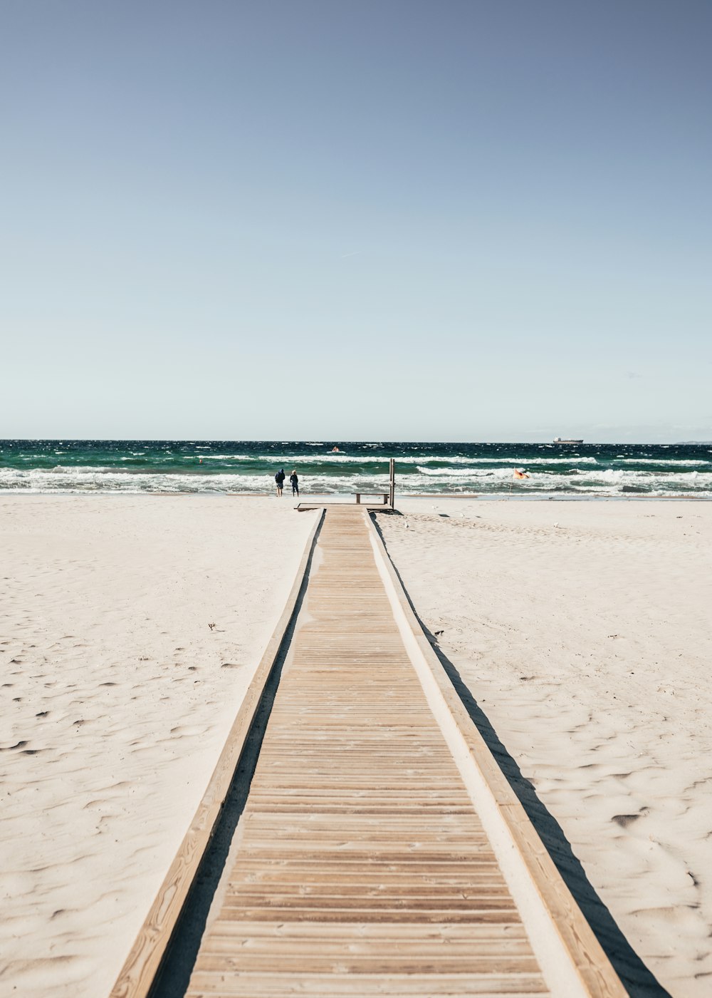 une longue passerelle en bois menant à la plage