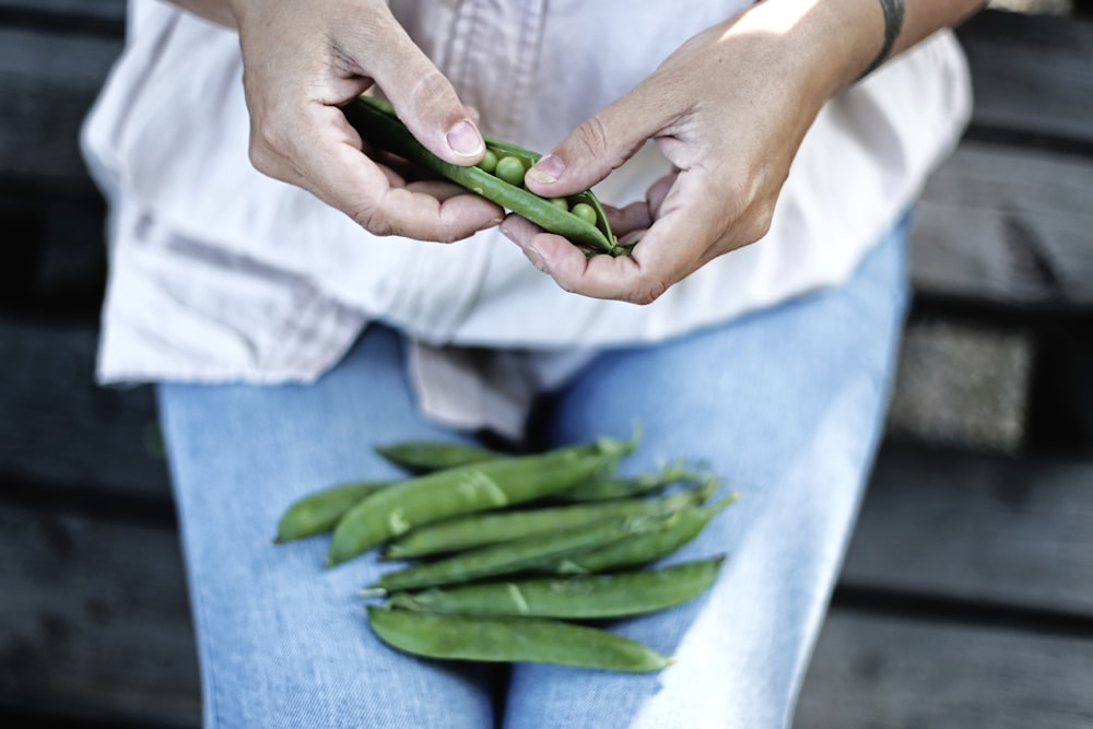 person holding pea pod in selective focus photography