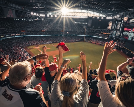 A lively group of fans cheering wildly at a sports game under bright stadium lights.