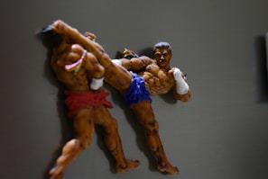 Two fighters locked in a grapple, expressions fierce, with shadows emphasizing their struggle