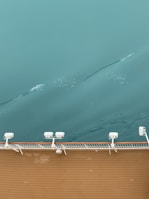 Close-up of polished teak wood and shimmering gold fixtures on a yacht’s railing.