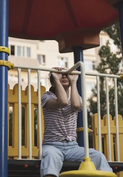a young girl sitting on a slide at a playground