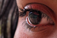 Close-up of an eye with a reflection of the eye chart visible on the cornea.