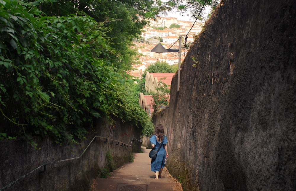 woman walking between wall and plant