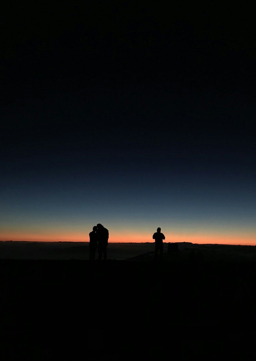 Silhouette von 3 Personen bei Sonnenuntergang