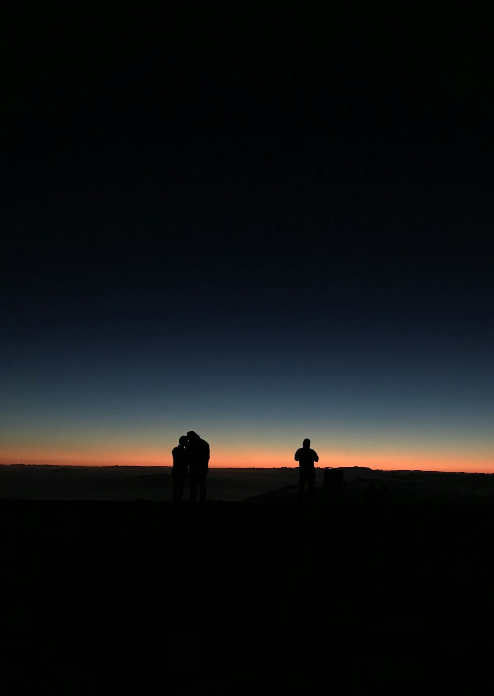 silhouette of 3 people at sunset