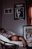 A person is relaxing in a papasan chair, holding a remote. The room features dark walls with several posters, including ones for The Weeknd's 'Trilogy' and the film 'Casablanca'. The lighting suggests a cozy, subdued atmosphere.