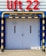 A large set of white industrial doors with handles, framed by sturdy blue metal. Above the doors, a bright red sign reads 'Lift 22' in bold letters. A yellow and black striped barrier runs horizontally above the doors, with matching striped poles on either side, adding a sense of caution. The ground is paved with concrete bricks.