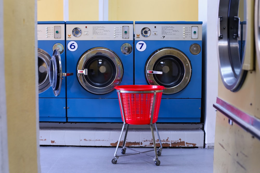 a red basket sitting in front of a row of washers