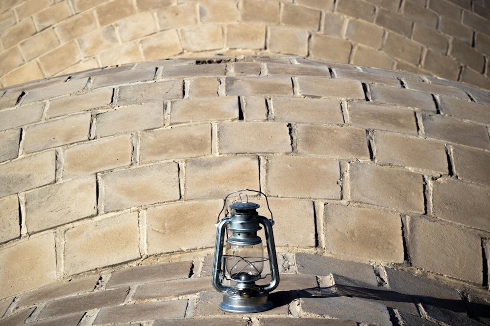 a small metal lantern sitting on a brick wall