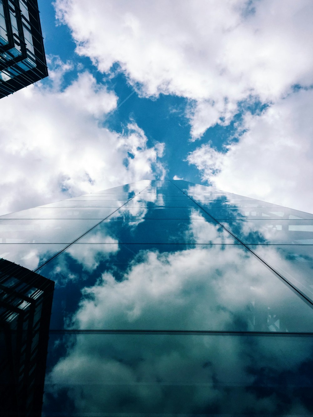 worm's-eye view of glass building across white clouds