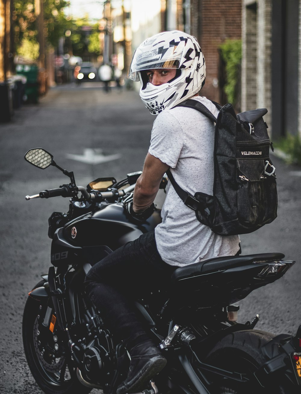 man wearing white crew-neck shirt riding black naked motorcycle