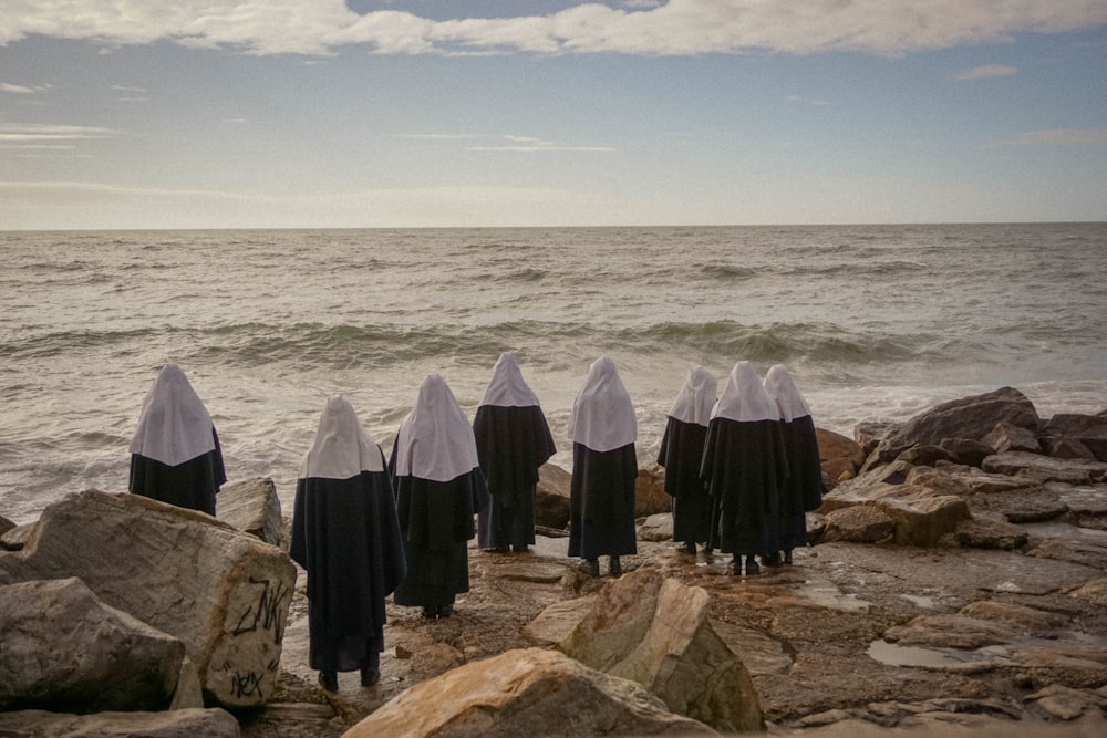 photography of people standing while facing on seashore during daytime