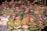 A market stall displays numerous bags of spices and herbs, each labeled with a price and name on red signs. The bags are neatly stacked, showcasing a variety of textures and colors. Some familiar spices such as mint, basil, and rosemary are visible.