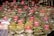 A market stall displays numerous bags of spices and herbs, each labeled with a price and name on red signs. The bags are neatly stacked, showcasing a variety of textures and colors. Some familiar spices such as mint, basil, and rosemary are visible.