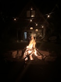 Evening view of the cabin with glowing lights and a fire pit outside.