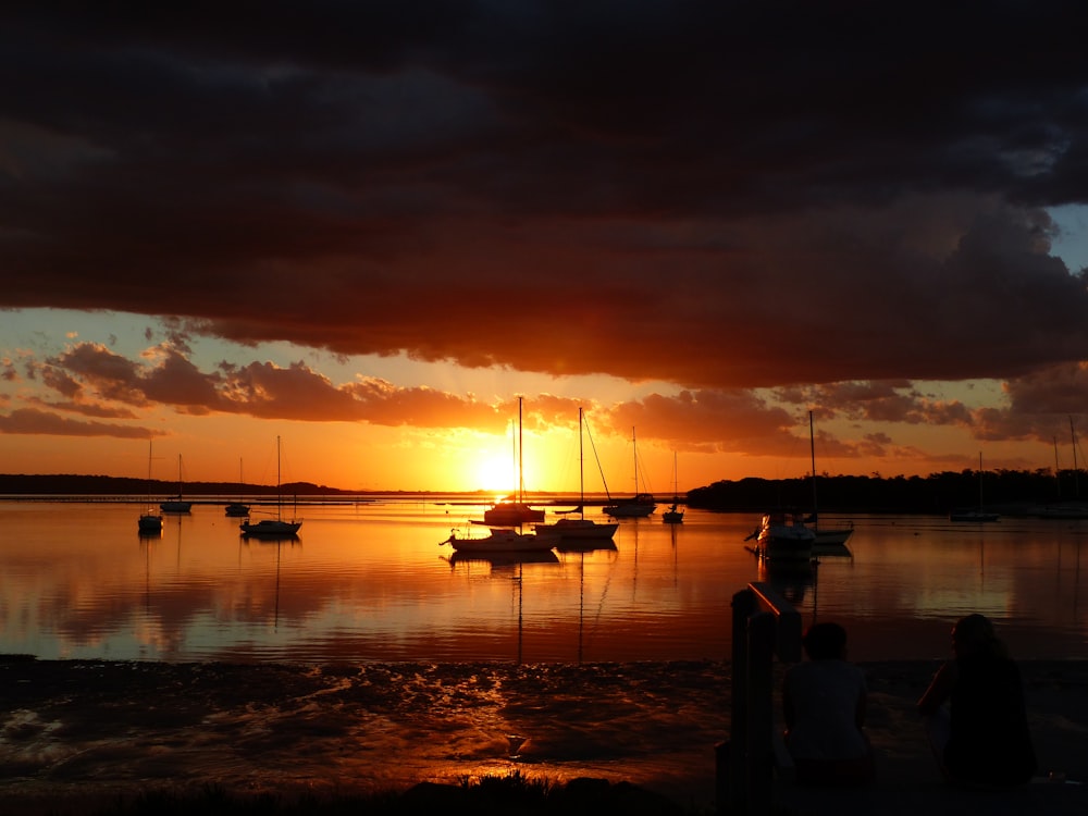 silhouette of boats on sea during golden hour