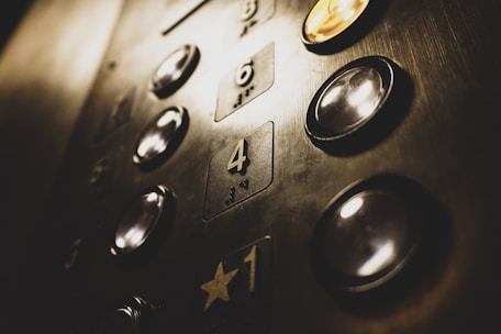 Close-up of elevator buttons and indicators in a residential building lobby.