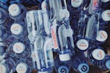 A collection of clear plastic water bottles with white caps, featuring a logo and design on the label, arranged in a compact layout.
