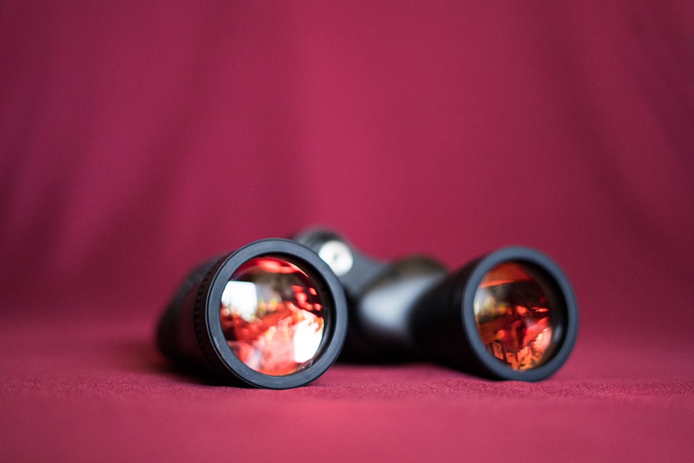 a pair of binoculars sitting on top of a red cloth