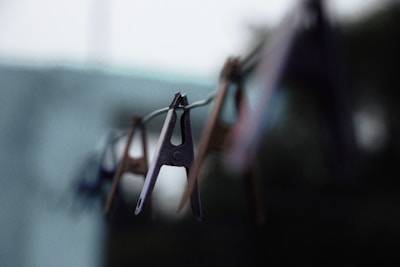 A close-up of stainless steel clothespins hanging on a clothesline.