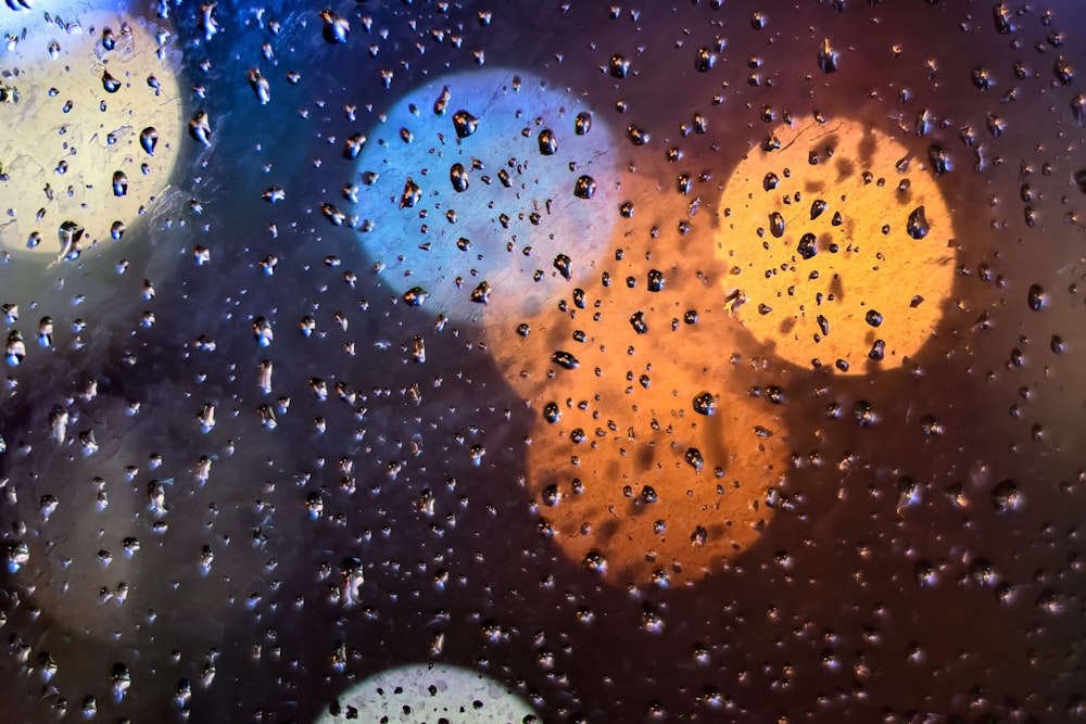 bokeh photography of water dew on clear glass pane