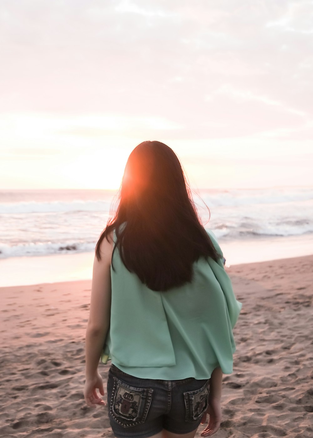 woman in teal top walking on beach