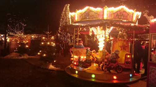 A vibrant carousel spinning with joyful children and colorful lights at dusk.