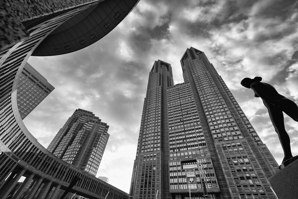 a statue of a man standing in front of tall buildings