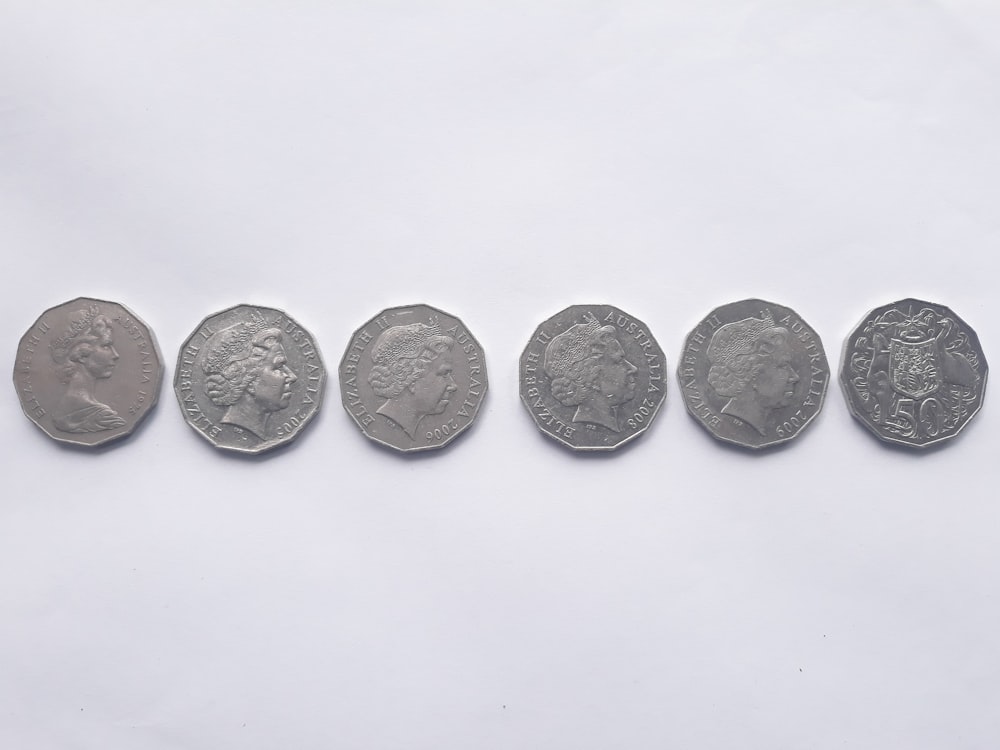 six silver-colored coins on white surface