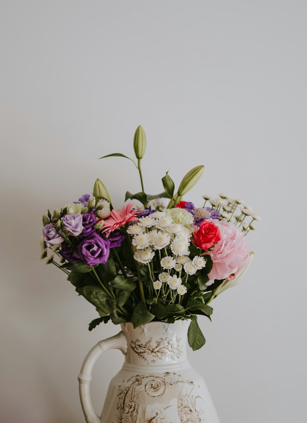 white, red, purple, and pink flowers on white ceramic vase