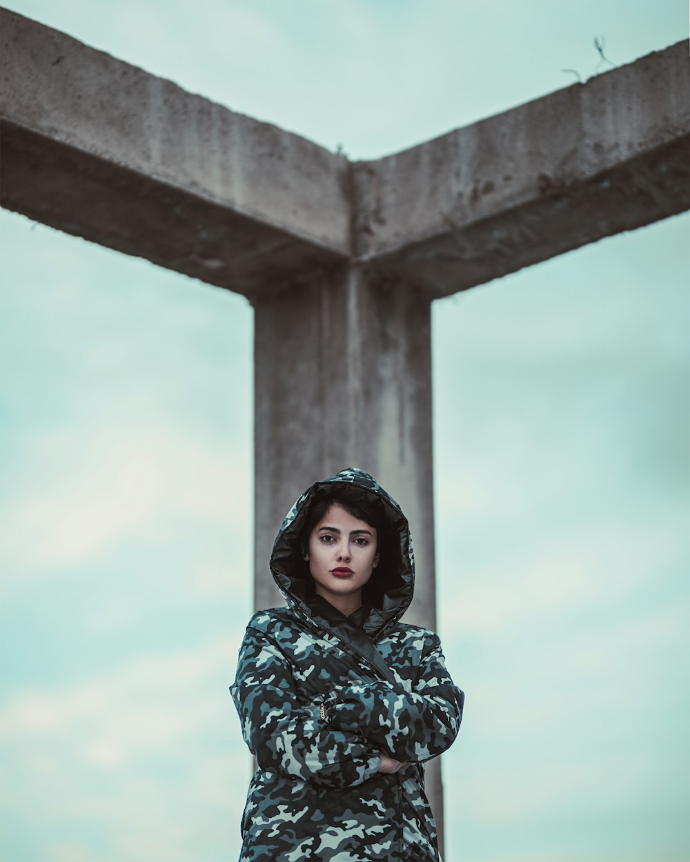 woman wearing black and white camouflage jacket standing near concrete post