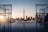 A scenic view of a city skyline with the CN Tower in the background, framed by two structures resembling hockey goals. The sunlight is casting a warm glow as it reflects off the water, creating a serene atmosphere.